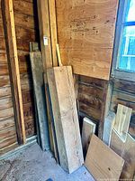 Lumber pieces leaning in corner including plywood sheet and boards