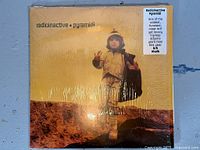 Front cover still in shrink wrap showing title and artist