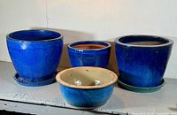 Front view of all four blue glazed planters with two visible saucers