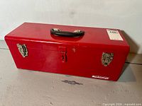 Front view of red Mastercraft steel toolbox showing handle, latches, lock hasp and logo