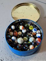 Open blue tin showing assorted marbles