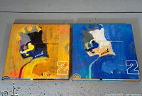 Front view of both box sets showing abstract artwork, yellow/orange for 2A and blue for 2B