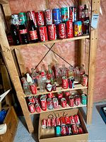 Three shelf view with multiple Coca-Cola cans and bottles