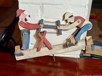 Front view of carved whirligig showing both workers and saw