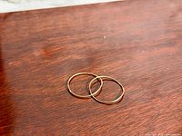 Pair of gold-tone hoop earrings on wood surface
