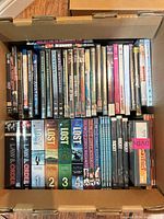 Box containing rows of DVDs and Blu-rays with visible titles and TV box sets