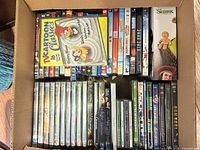 Open box showing upper layer of mixed DVD and Blu-ray cases including Cartoon Classics set, Marvel titles, Shrek gift box