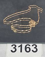 Full view of twisted 14K gold chain laid out showing clasp and design