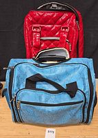 Front view showing both pieces: red quilted suitcase behind, blue faux snakeskin duffel in front