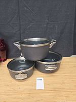 Three Calphalon Premier grey nonstick pots stacked with their glass lids