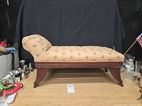 Side view of upholstered child's chaise chair on wooden legs with casters