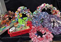All seven rag wreaths arranged behind basket of ribbon spools and gift-wrap roll