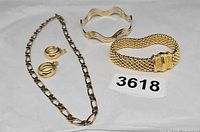 All items: link chain necklace, hoop earrings, mesh bracelet, wavy bangle