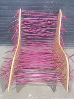 Front view showing full chair, plywood sides and pink rods