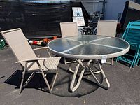 Round glass patio table with three sling chairs overview