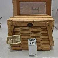 Front view of wooden picnic basket showing weave, clasp, lid, hang tag