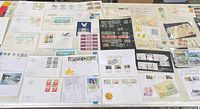Collection of worldwide stamps, first day covers, souvenir sheets, postcards and letters spread on table