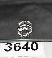 Front view of sterling silver wavy ring on reflective surface