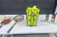 Full lot view showing racquets, ball hopper, Penn cans