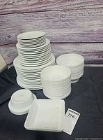 Stacks of round plates, bowls and square plates on table