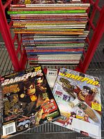 Front view showing two sample GamePro issues (Donkey Kong 64 and Harry Potter covers) atop stacked magazines in crate