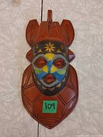 Front view of carved wood Amarula wall mask showing beadwork and overall design