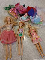 All three Barbie dolls with assorted clothing pile
