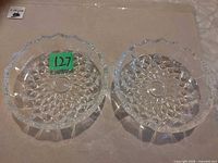 Top view of two matching clear cut glass candy dishes showing scalloped rims and starburst pattern