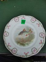 Front view showing plate design, scalloped rim, floral border and fish scene