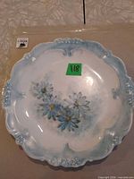 front of porcelain plate showing scalloped edge and painted blue daisies