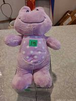Front view of purple plush frog rattle showing white polka-dot belly and overall condition