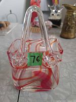 Front view of clear glass handbag-shaped vase with red swirl pattern