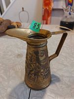 Brass jug front view showing ship relief and handle