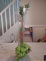 Tall clear glass vase with faux stems and green bow accent