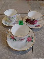 Three teacups on saucers showing patterns and gold trim