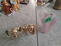 Pink glass elephant figurine and two gold-tone elephant-head perfume bottles on tabletop