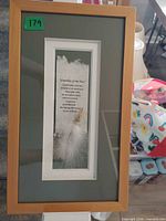 Framed poem wall art with feather and charm visible in wooden frame
