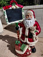 Full view of 50 in resin Santa statue with chalkboard, sack and gifts