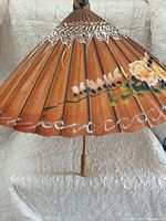 Open parasol showing terracotta canopy, floral painting, wood handle
