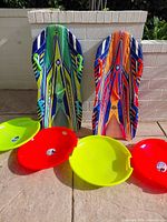 Two multicolor Sno-Storm bodyboards and four snow discs displayed