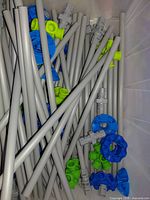 Gray plastic poles and blue and green connectors in storage bin