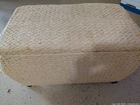 Closed woven seagrass trunk on casters showing overall appearance and frayed corner