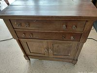 Front view showing drawers, cabinet doors, glass knobs, castors