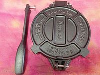 Top view of closed cast-iron tortilla press with detached handle
