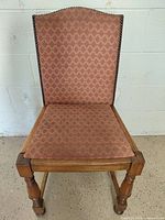 Front view showing upholstery pattern, nailhead trim, turned legs