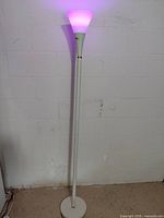 Full view of white torchiere lamp lit purple
