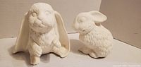 Front view of both white ceramic bunny figurines