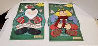 Front view of both Create A Wreath Buddy kits showing Santa and doll designs in sealed packages