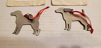 Front view of both pewter dog ornaments with red ribbons and bone tags