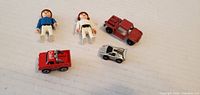Group shot of 2 Playmobil figures and 3 toy cars